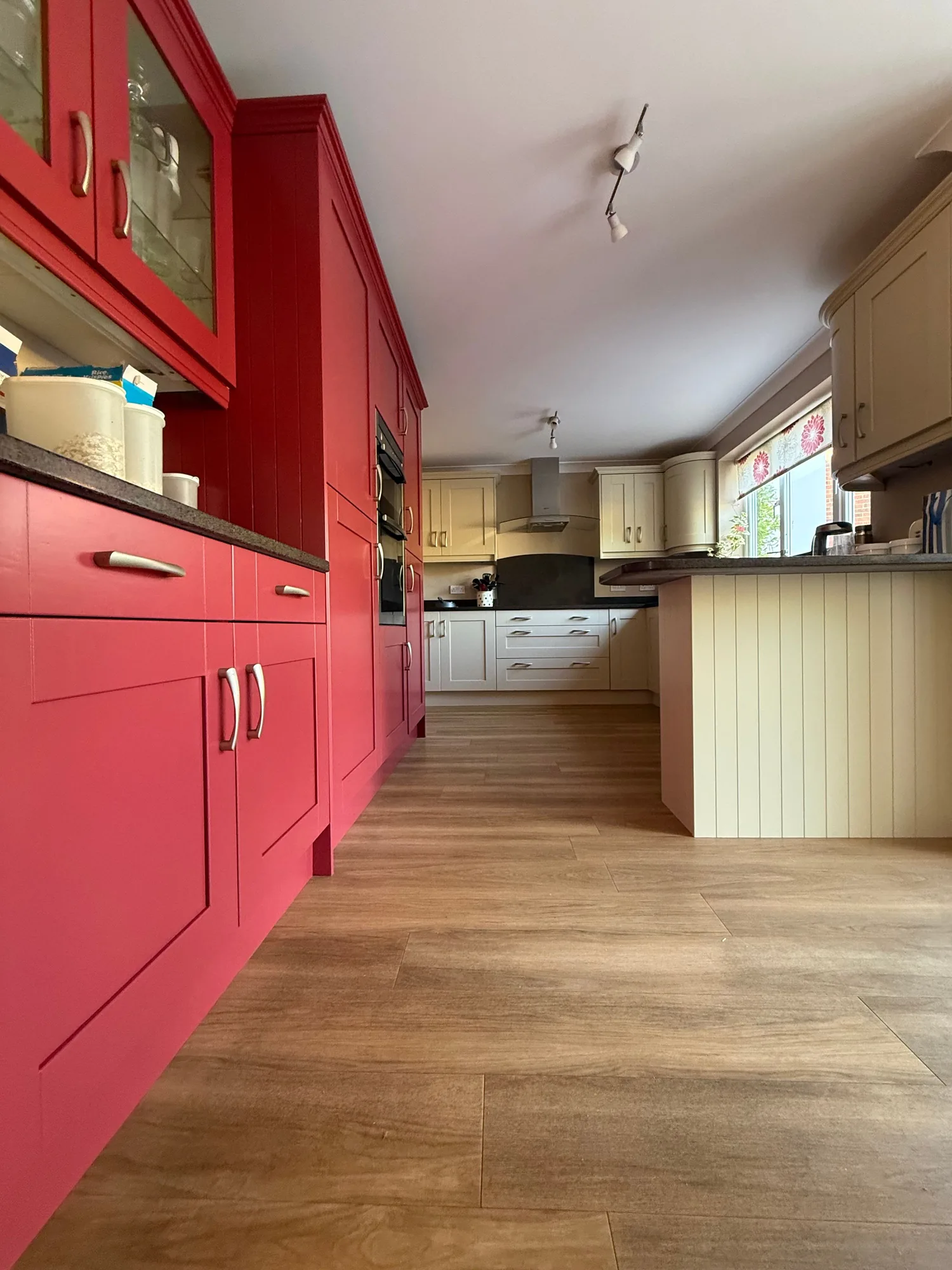 Red and cream kitchen units resprayed, with a wood effect floor