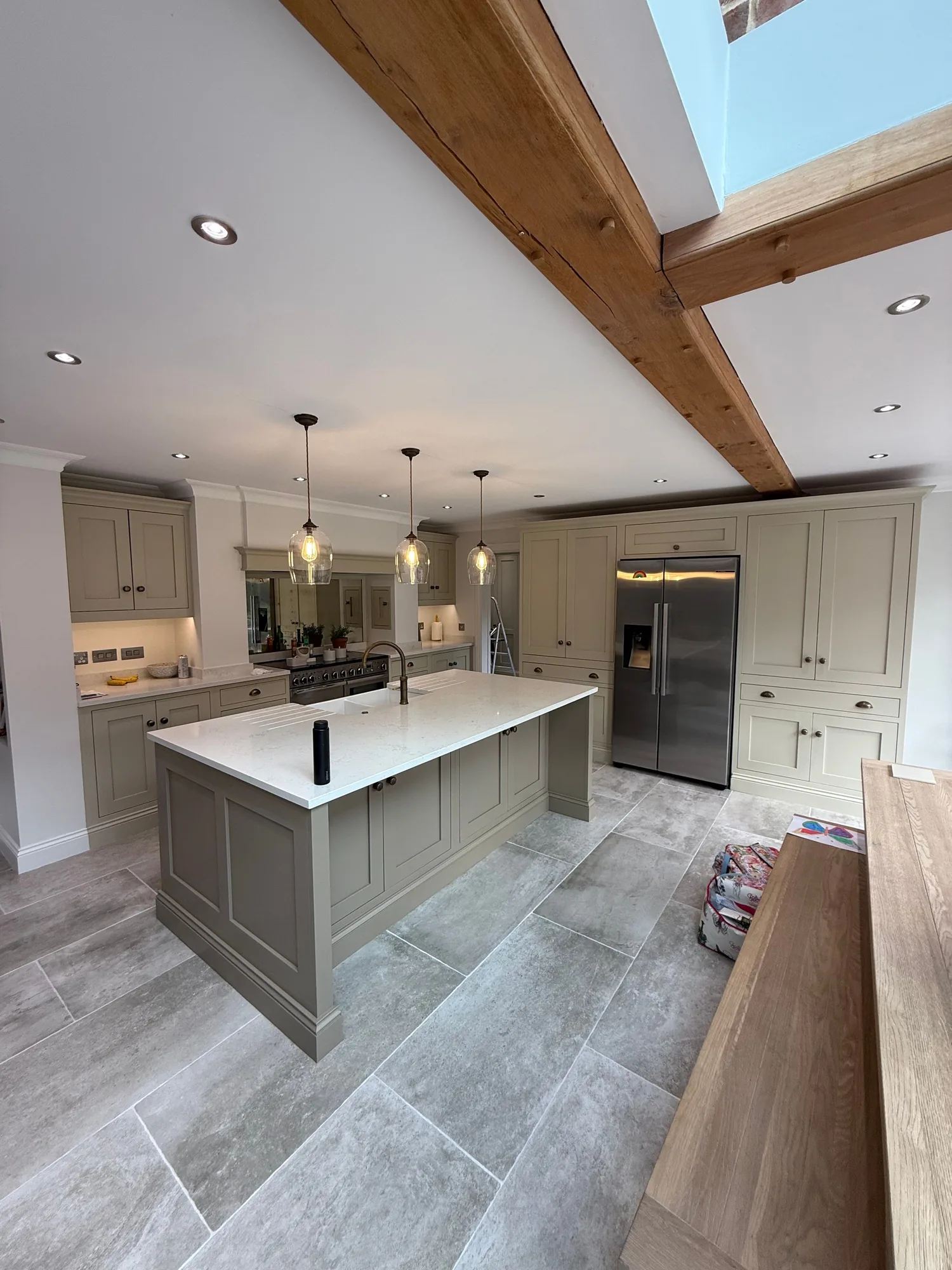 Grey green island kitchen under an exposed beam ceiling