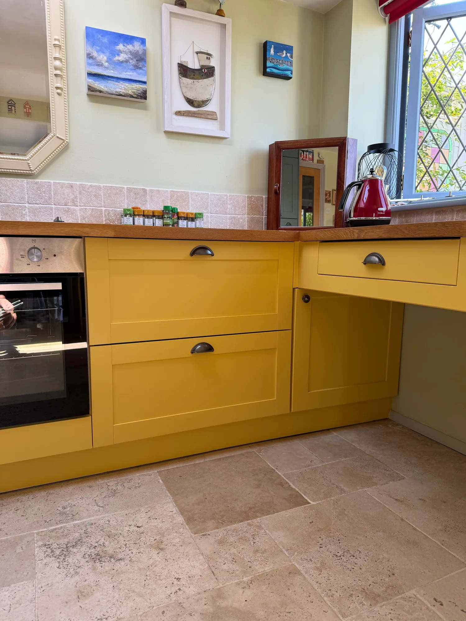 Yellow kitchen units with a wood worktop and integrated oven