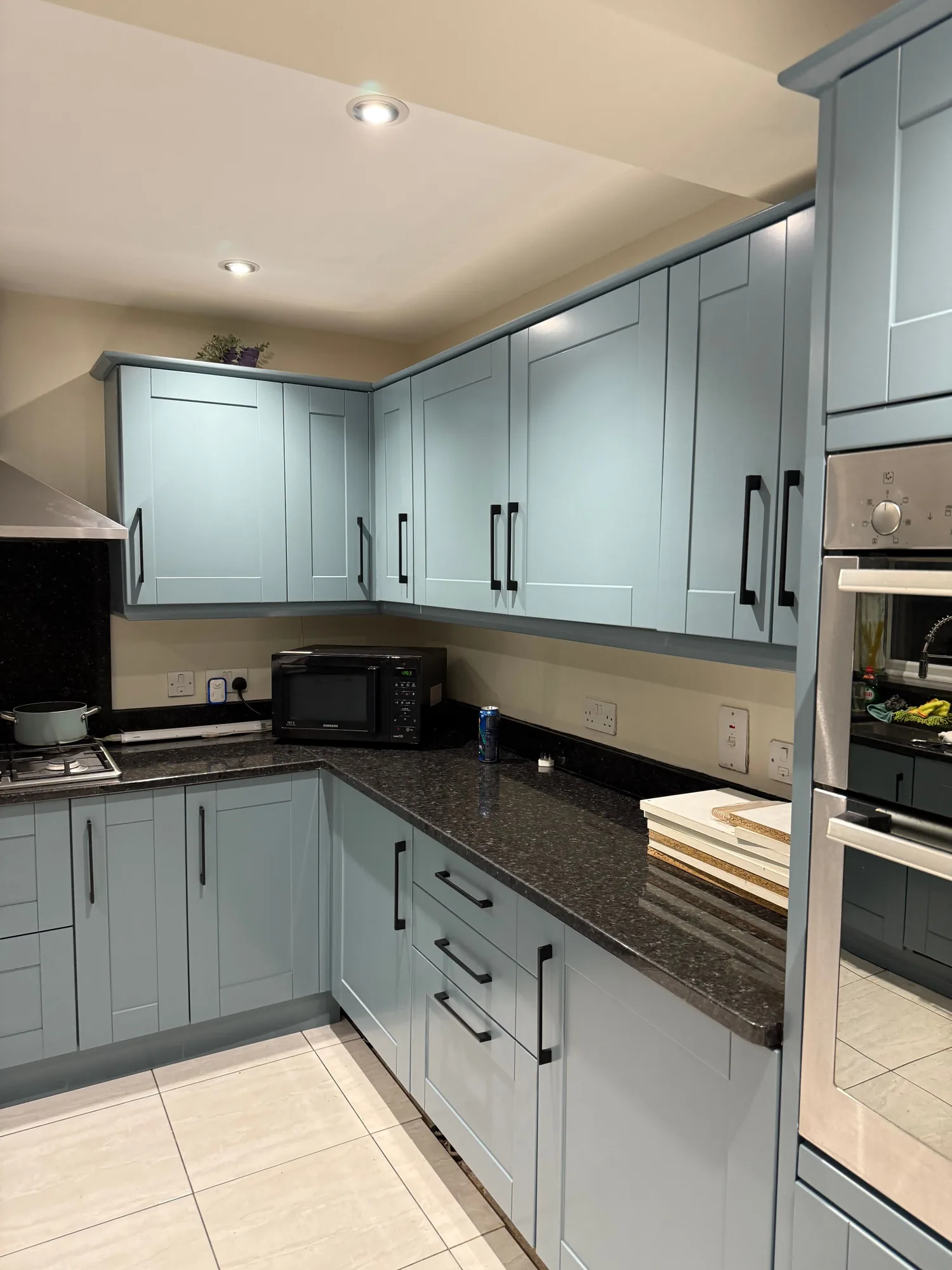 Pale green kitchen with dark worktop and integrated appliances