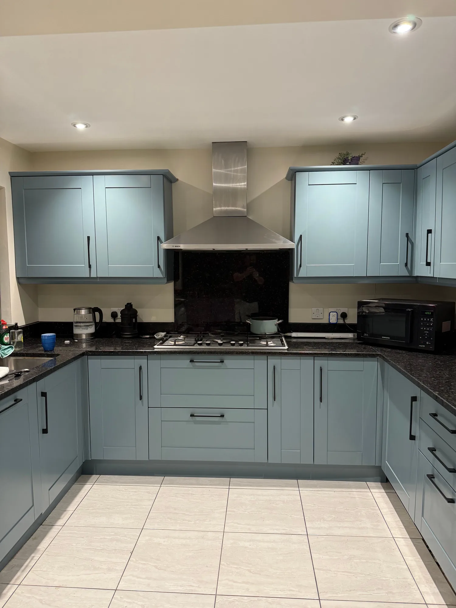 Grey green kitchen with extractor hood and tiled floor